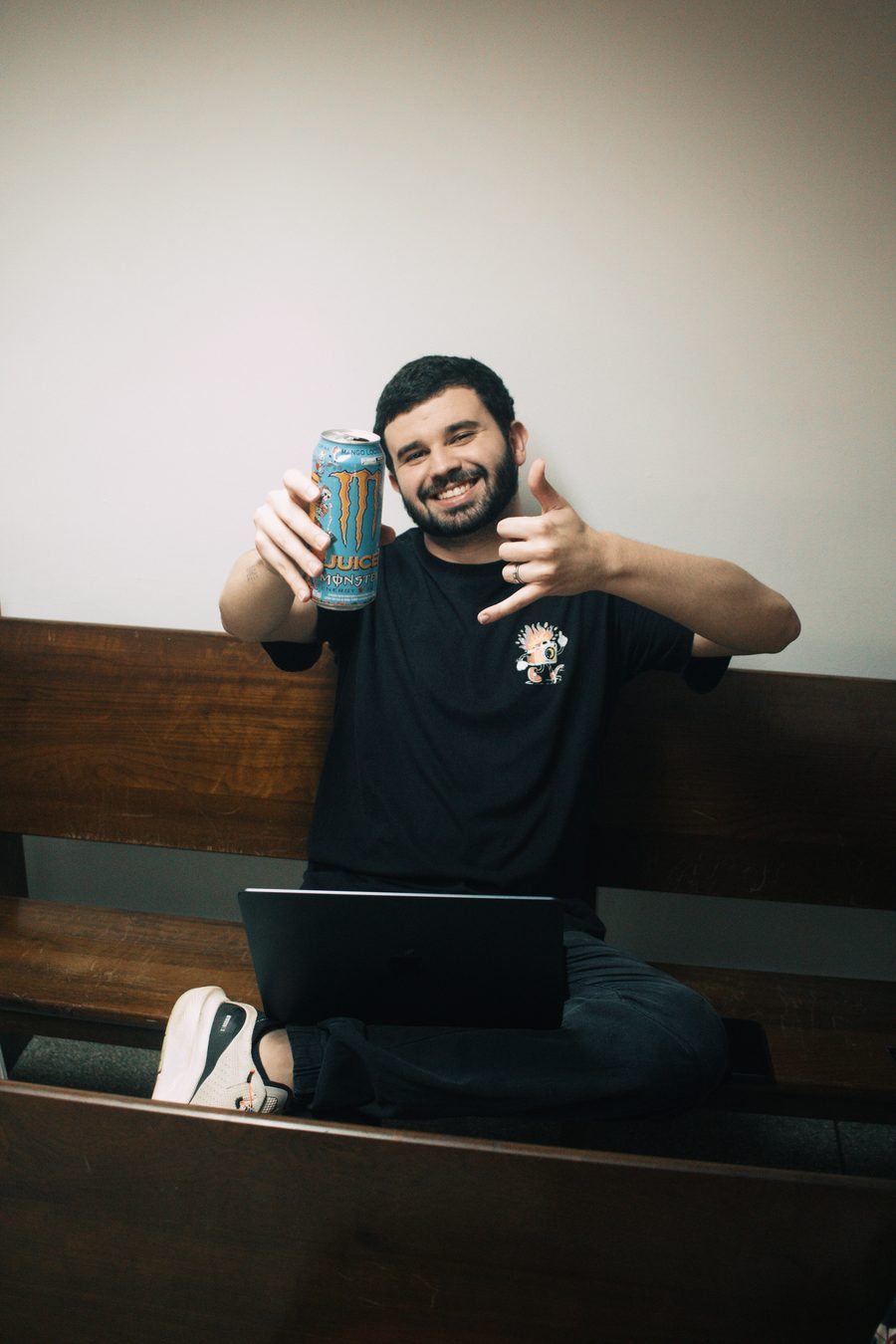 Gabriel sentado num banco com o notebook, fazendo joinha